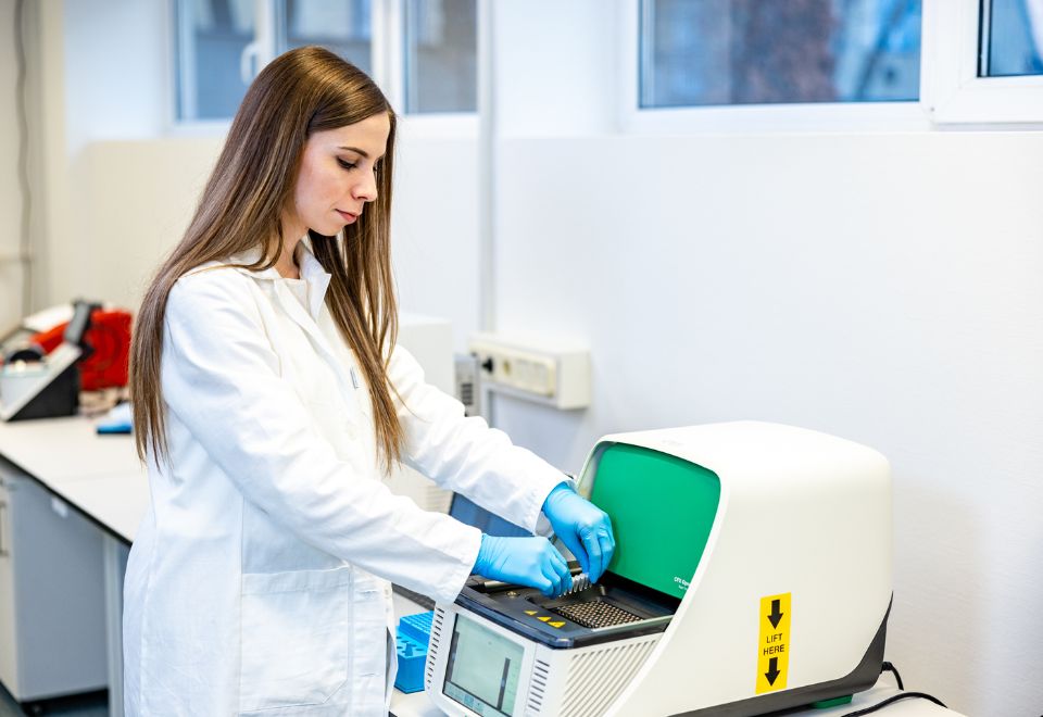 A Clinomics Diagnostic kutatója a BioRad Opus Dx In vitro diagnosztikai minősítésű, nagy pontosságot és magas precizitást biztosító készüléke előtt.